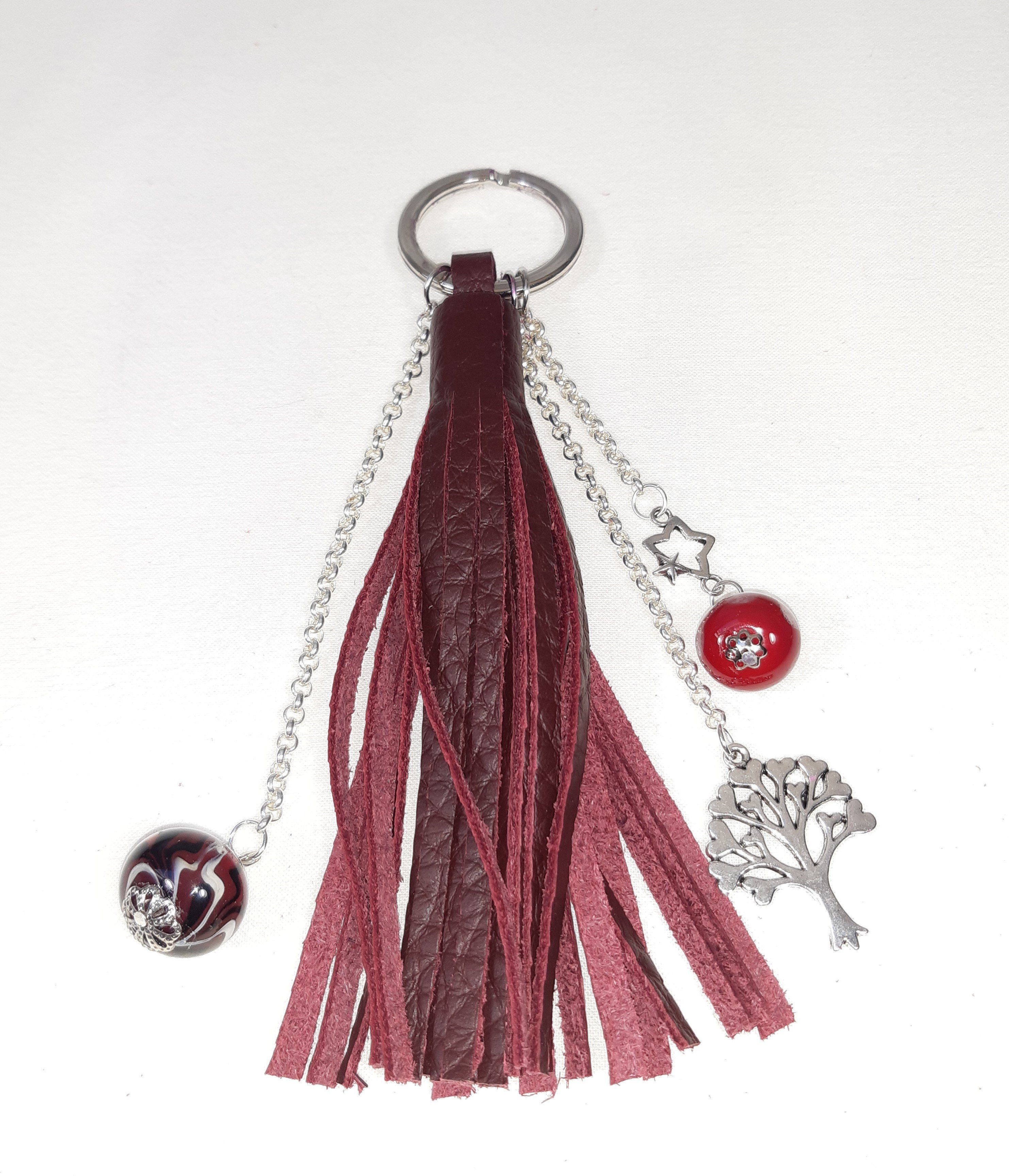 Bijou de sac, pompon cuir coloris bordeaux avec perles en verre filé.